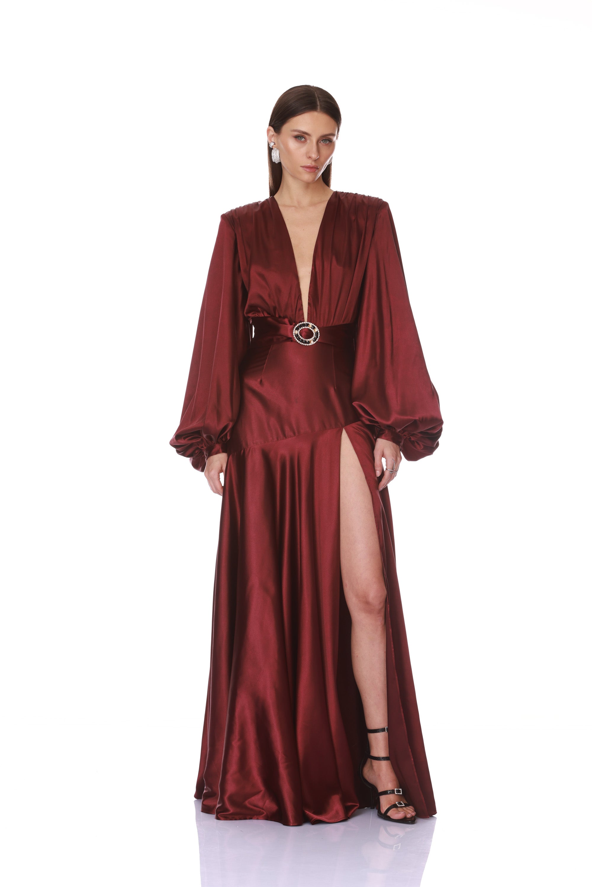 Woman wearing a burgundy satin evening gown with a belt on a white background