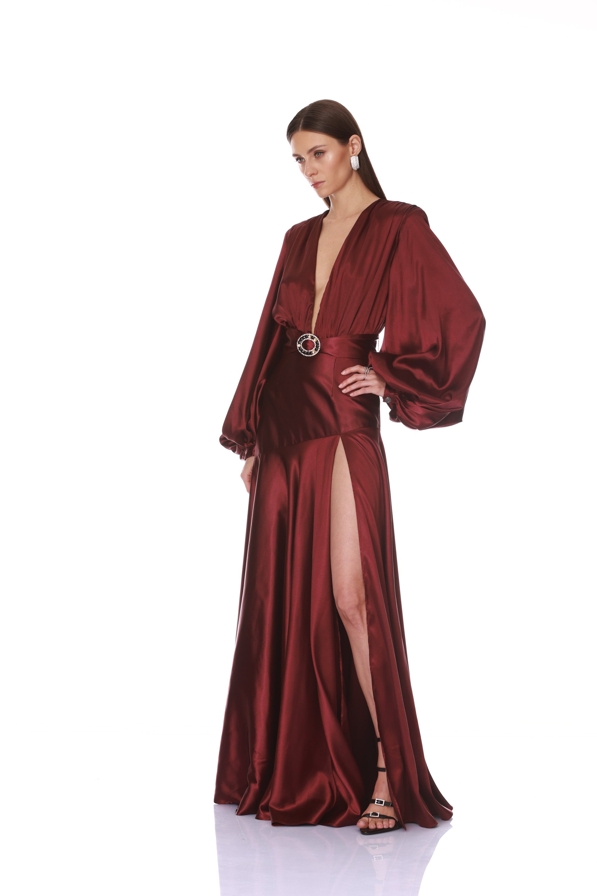 Woman wearing a burgundy satin evening gown with a belt on a white background