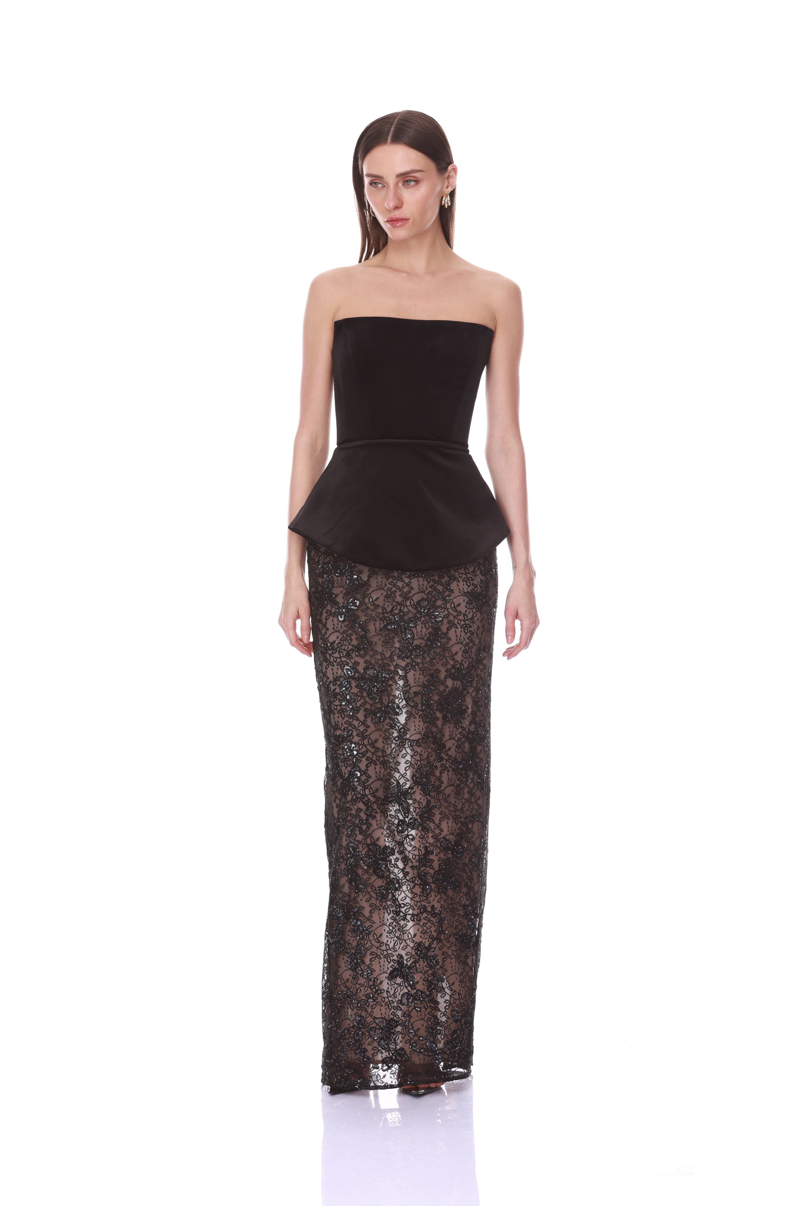 A model wearing a black strapless peplum top and a matching black lace maxi skirt, photographed against a solid white studio background.