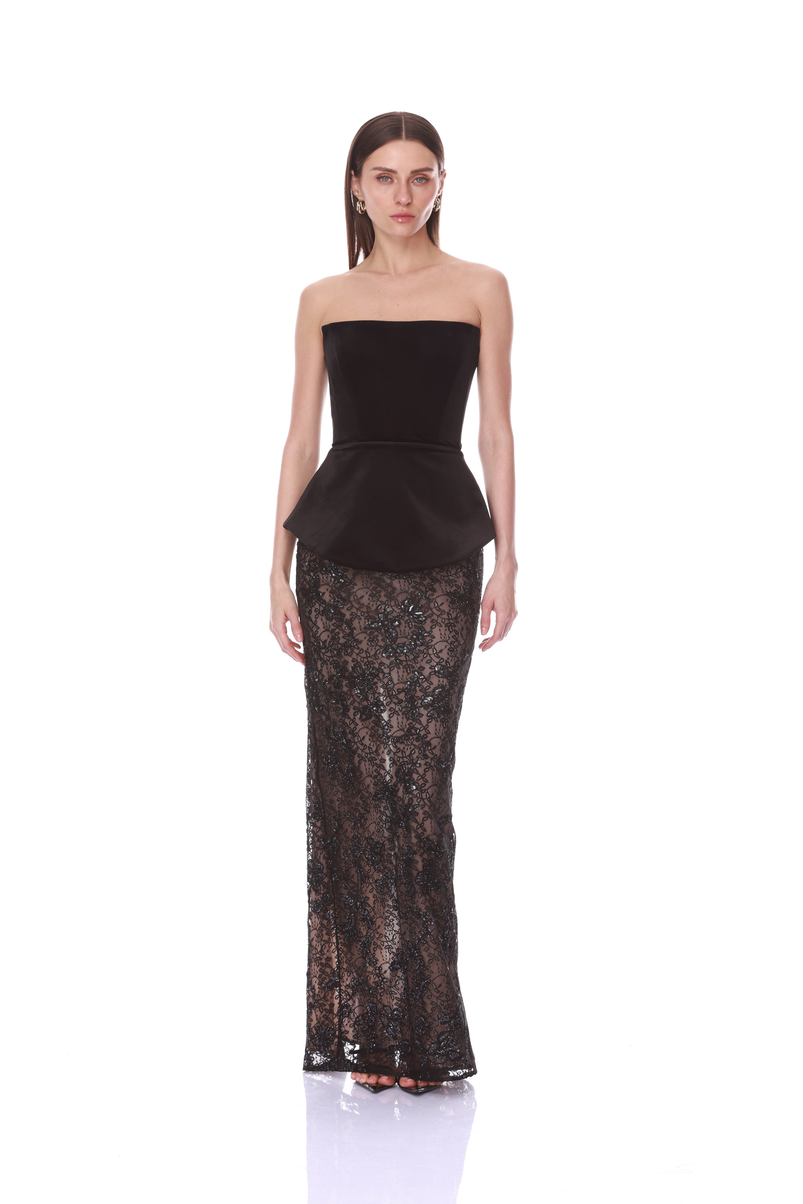 A model wearing a strapless black peplum top and a matching sheer black lace floor-length gown, photographed against a plain white studio background.